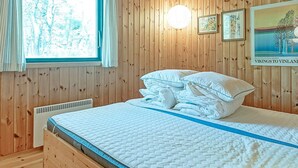Una habitación con paneles de madera, una cama, una ventana y un cartel en la pared.