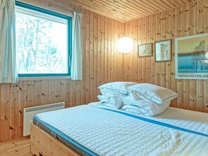 A wooden-paneled room with a bed, a window, and a poster on the wall. - Cozy Holiday Home in Bornholm near Sea (Nexø)
