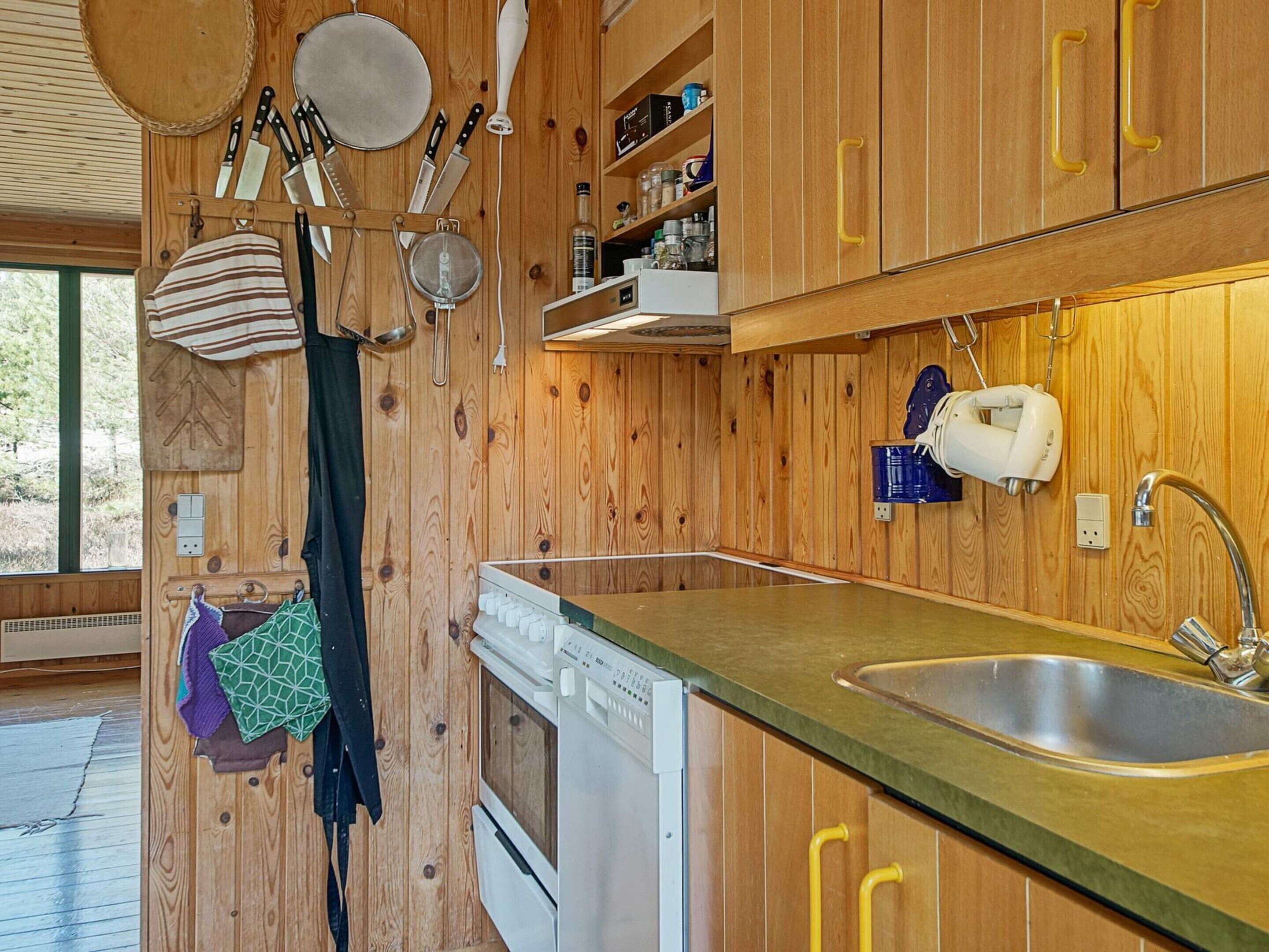 A kitchen with wooden cabinets, a stainless steel sink, and a dishwasher.