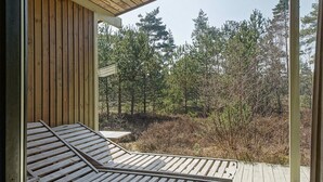 Una terraza de madera con banca integrada, con vista a un área boscosa.