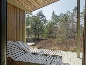 A wooden deck with a built-in bench, overlooking a forested area. - Cozy Holiday Home in Bornholm near Sea (Nexø)