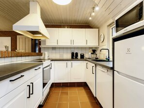 A modern kitchen with white cabinets, a built-in oven, a microwave, and a dishwasher. - 5 Star Holiday Home in Vaeggerlose (Vaeggerlose)