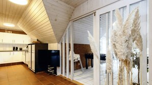 A spacious kitchen with white cabinets, a black refrigerator, and a flat-screen TV. - 5 Star Holiday Home in Vaeggerlose (Vaeggerlose)