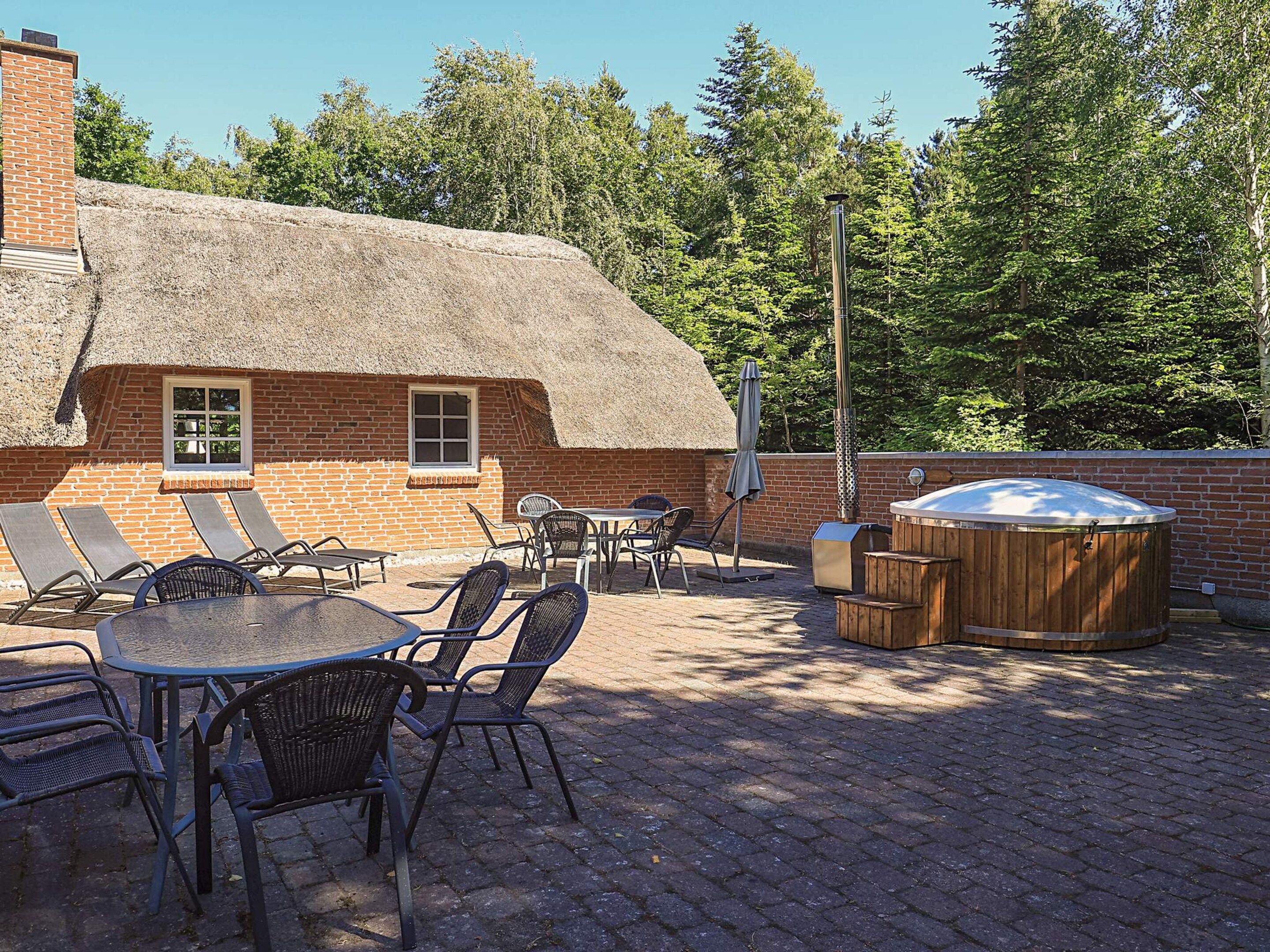 Une terrasse avec un bâtiment en briques, des sièges extérieurs et un jacuzzi.
