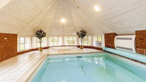 An indoor swimming pool with a tiled floor, a brick wall, and a ceiling with wooden panels. - 5 Star Holiday Home in Vaeggerlose (Vaeggerlose)