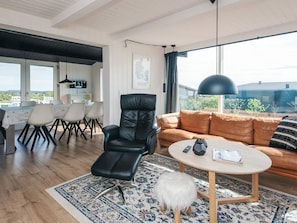 A modern living room with a leather chair, a round coffee table, and a sofa. - 4 Star Holiday Home in Ebeltoft (Ebeltoft)