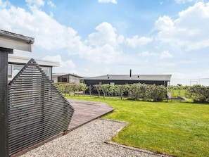A modern building with a sloped roof, a paved driveway, and a well-maintained lawn with young trees. - 4 Star Holiday Home in Ebeltoft (Ebeltoft)