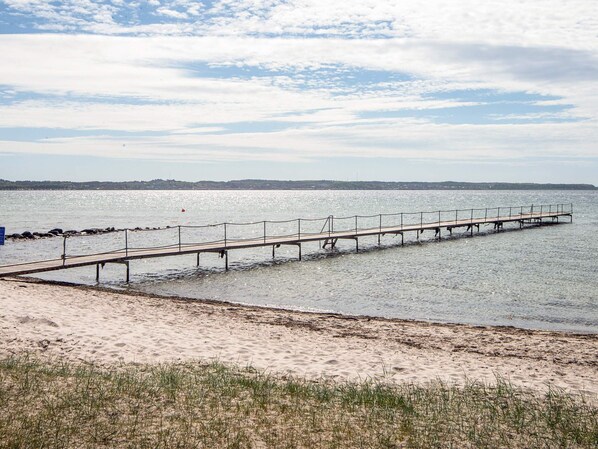 A pier extending into calm water with a sandy beach in the foreground. - 4 Star Holiday Home in Ebeltoft (Ebeltoft)