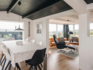 A modern interior with a dining area, a sofa set, and a large window offering a view. - 4 Star Holiday Home in Ebeltoft (Ebeltoft)