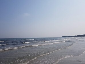 A beach with waves, a clear sky, and a distant shoreline.