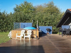 A wooden deck with outdoor seating, a barbecue grill, and a covered area with a blue roof.