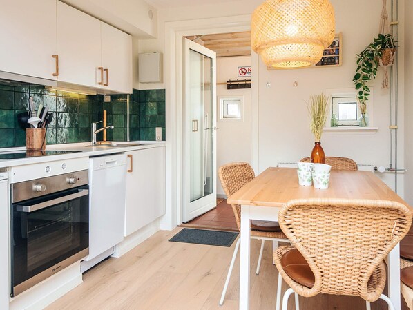Une cuisine moderne avec des armoires blanches, un four encastré et un dosseret de carrelage vert.