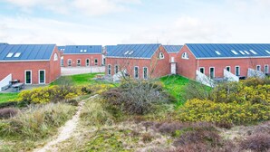Une rangée de bâtiments en briques rouges, dotés de toits plats, et un chemin de gravier menant à ces bâtiments.