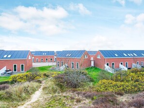 Række rødstensbygninger med flade tage og en grussti, der fører hen til dem.