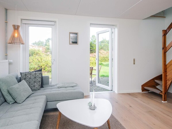 Una sala de estar moderna con un sofá gris, una mesa de centro blanca y una escalera de madera.
