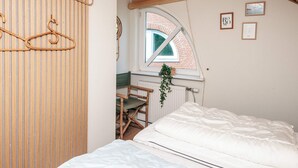 Une chambre à coucher avec un lit, une fenêtre donnant sur un immeuble en briques et un plafond en bois.