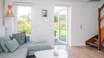 Una sala de estar moderna con un sofá gris, una mesa de centro blanca y una escalera de madera.