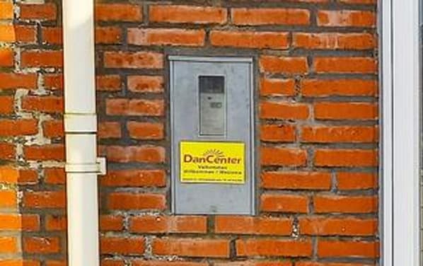 A brick wall with a utility box and a yellow sign labeled 'DanCenter.' - 6 Person Holiday Home in Romo (Rømø)