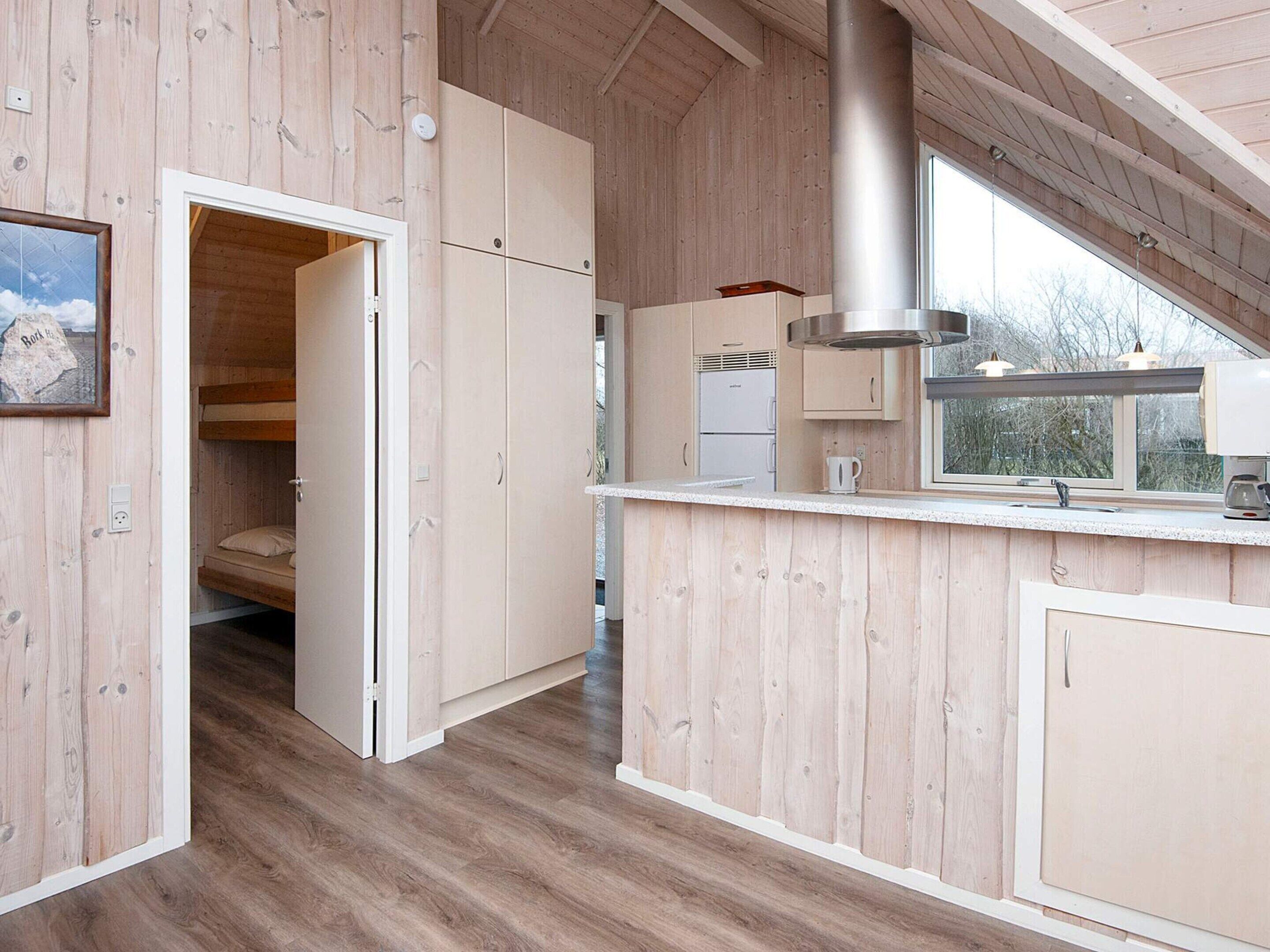 Une cuisine moderne avec des meubles en bois, une cuisinière encastrée et une fenêtre donnant sur l’extérieur.