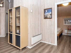Una habitación con un armario de madera, una cama, un radiador y un cuadro enmarcado en la pared.