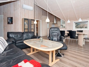 A modern living room with a sofa, a dining table, and a chair. - 9 Person Holiday Home in Hemmet (Hemmet)