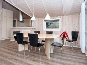 Una cocina moderna con paredes de madera, una mesa redonda y sillas negras.