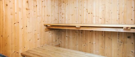 Un sauna en bois, avec des bancs et une étagère.