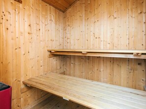 En bastu gjord av trä, med bänkar och en hylla.