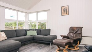 A modern living room with a sectional sofa, a leather armchair, and a black ottoman.