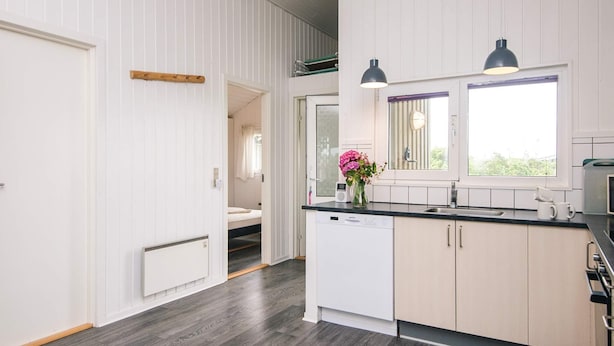 A modern kitchen with white cabinetry, a black countertop, and a window with a view.
