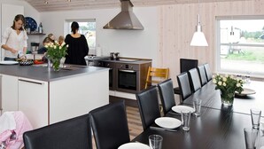 A modern kitchen with a central island, dining area with chairs, and a large window.