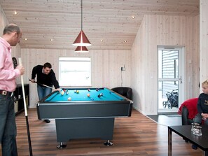 A pool table in a room with wooden walls and a sloped ceiling, a window with natural light, and a door leading outside. - 5 Star Holiday Home in Idestrup (Idestrup)