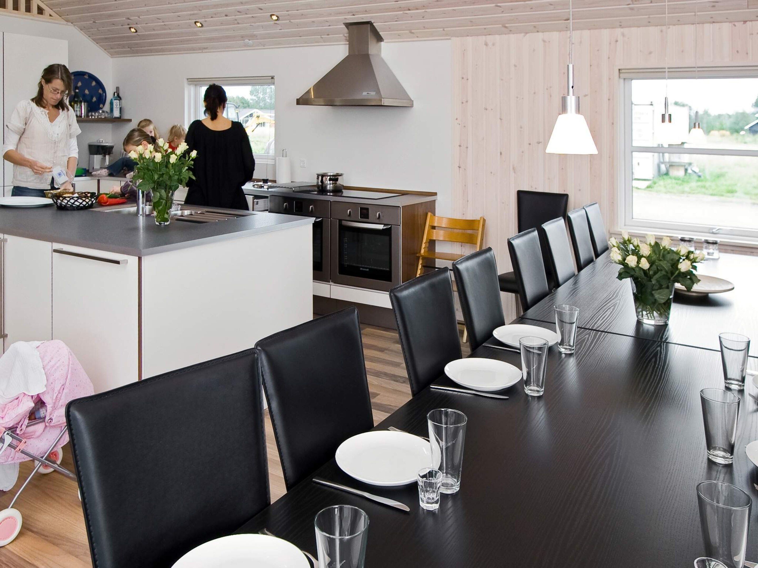 Une cuisine moderne dotée d’un îlot central, d’un coin repas avec des chaises et d’une grande fenêtre.