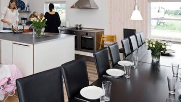 Une cuisine moderne dotée d’un îlot central, d’un coin repas avec des chaises et d’une grande fenêtre.