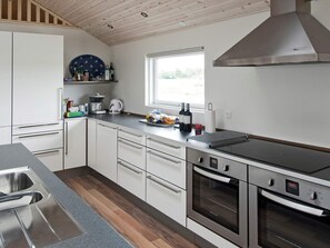 Una cocina moderna con electrodomésticos de acero inoxidable, horno empotrado y ventana que proporciona luz natural.