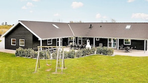 A two-story building with a covered patio area and a swing set in the foreground.