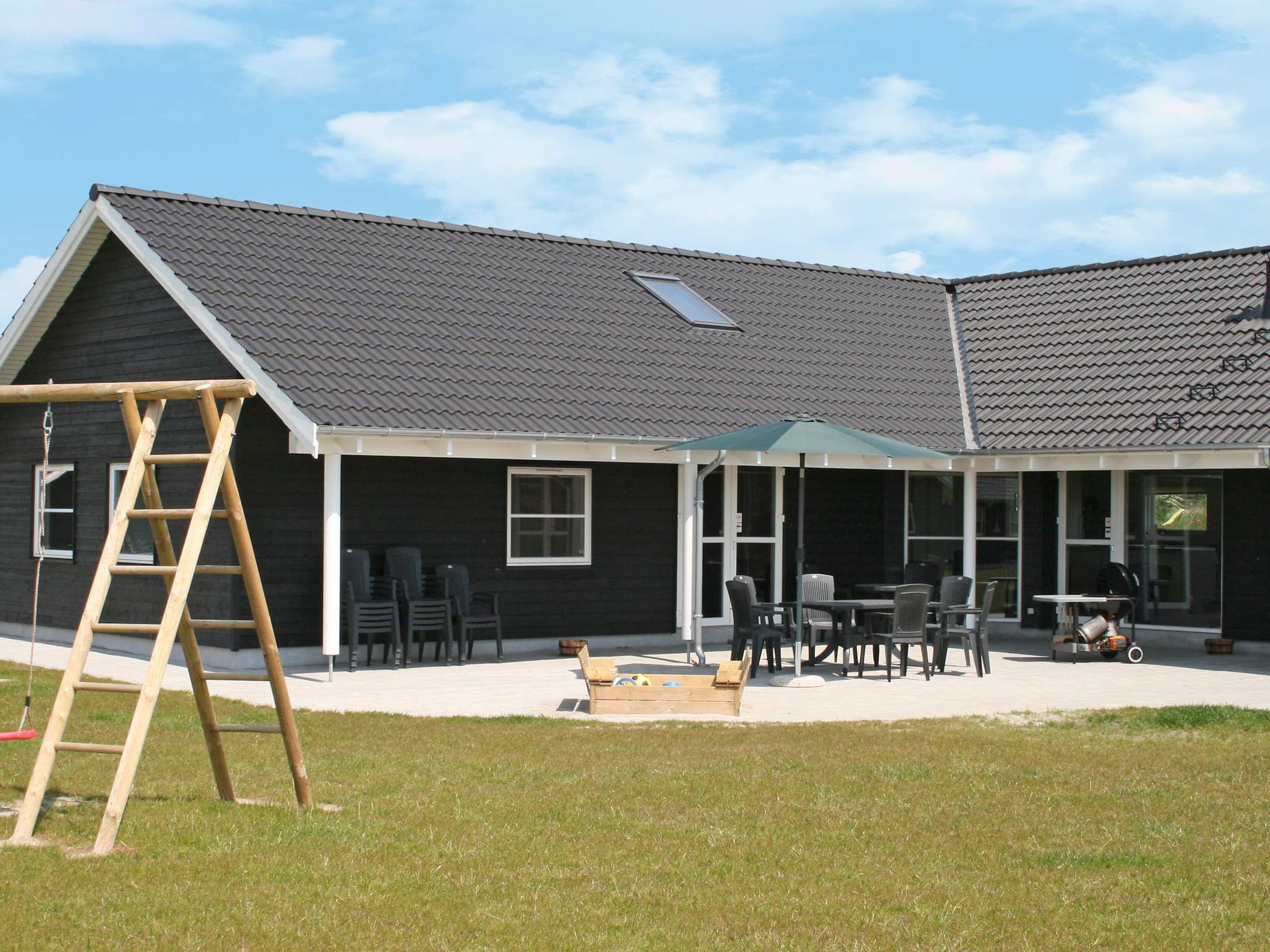 A house with a covered patio area, a wooden ladder, and outdoor furniture.