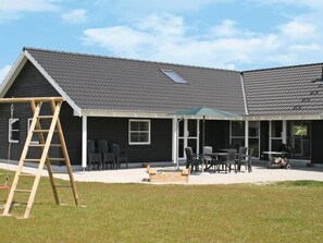 A house with a covered patio area, a wooden ladder, and outdoor furniture. - 5 Star Holiday Home in Idestrup (Idestrup)
