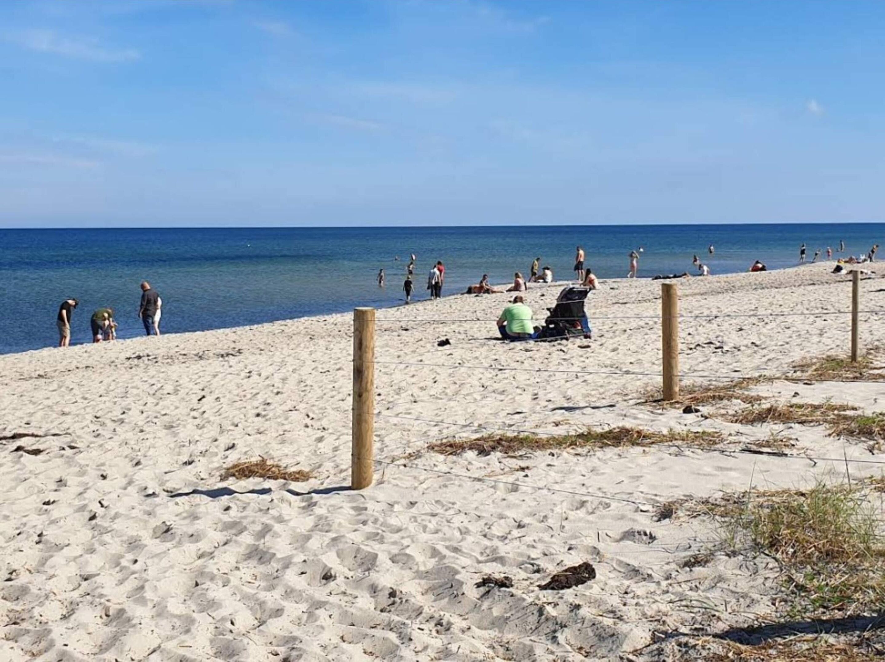 Ein sandiger Strand mit blauem Himmel und ruhigem Meer.
