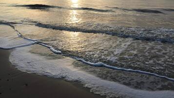 Una spiaggia con onde che lambiscono dolcemente la riva, riflettendo la luce del sole.