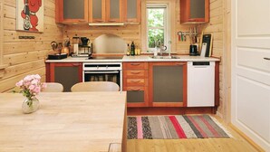 A compact kitchen with wooden cabinets, a coffee machine, and a dishwasher. - Stylish Holiday Home in Føllenslev near Sea (Follenslev)