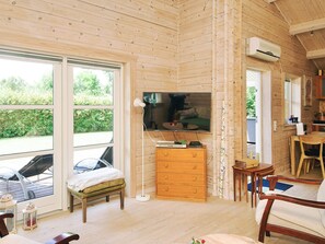 A wooden interior with a television, a wooden dresser, and a dining area. - Stylish Holiday Home in Føllenslev near Sea (Follenslev)