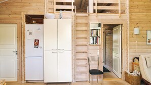 A wooden interior with a white refrigerator, a chair, and a bookshelf. - Stylish Holiday Home in Føllenslev near Sea (Follenslev)