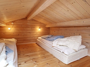 Un dormitorio de cabaña acogedor, con paredes de madera, una cama, un colchón y dos luces fijadas a la pared.