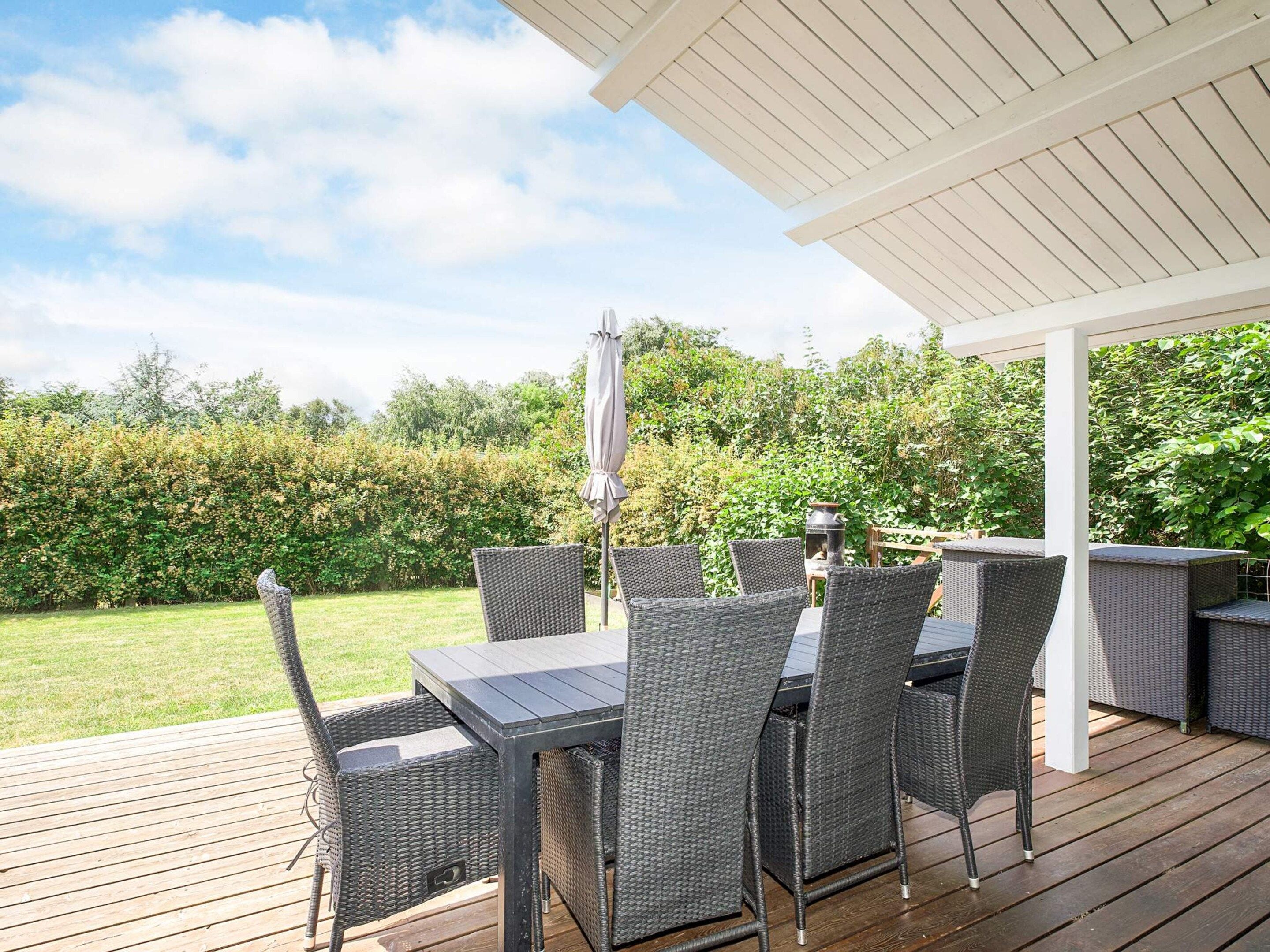 Eine Terrassengruppe mit Korbmöbeln und einer Pergola.