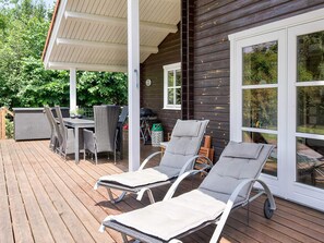A wooden deck with outdoor furniture, including a table and chairs, and two lounge chairs. - Stylish Holiday Home in Føllenslev near Sea (Follenslev)