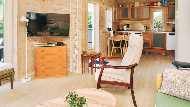 A wooden interior with a TV, wooden cabinets, a dining area, and a sofa. - Stylish Holiday Home in Føllenslev near Sea (Follenslev)