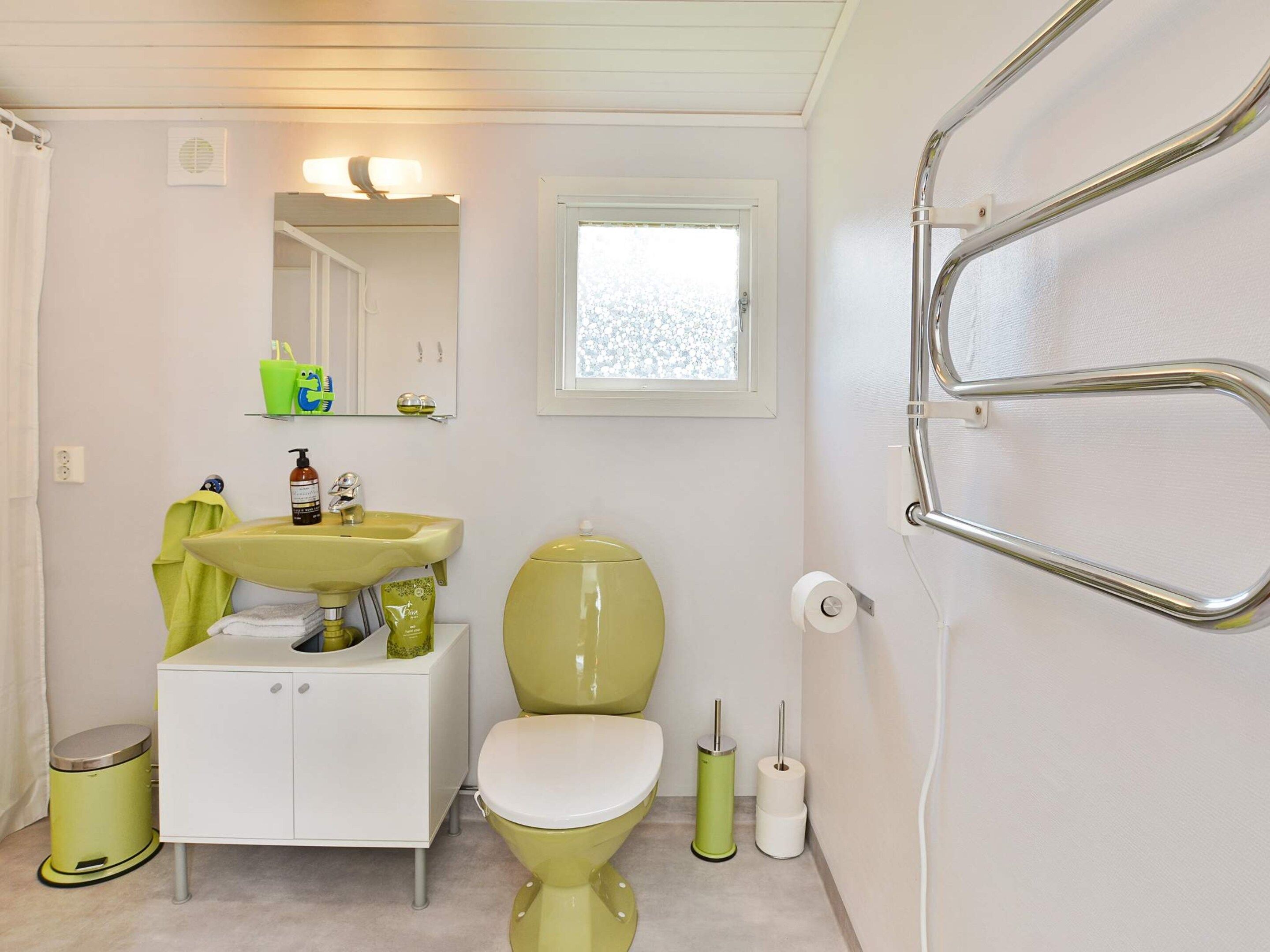 A bathroom with a white sink, green toilet, and a mirror above the sink.