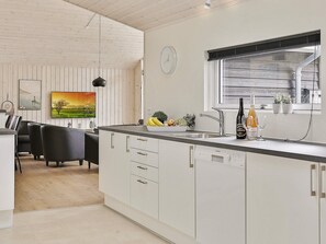Eine moderne Küche mit weißen Schränken, einem eingebauten Backofen und einem Fenster mit Jalousien.