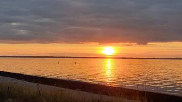 A sunset over a calm body of water with a distant shoreline.